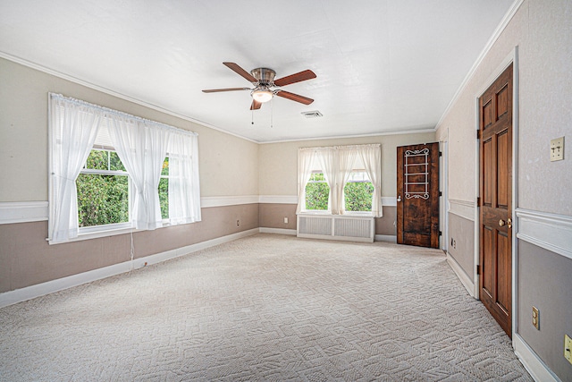 carpeted empty room with a healthy amount of sunlight, ornamental molding, and ceiling fan