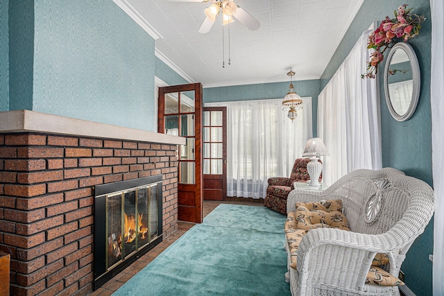 living area with crown molding, ceiling fan, and a brick fireplace