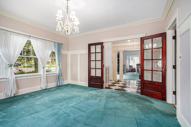 unfurnished room featuring decorative columns, ornamental molding, dark colored carpet, and a notable chandelier