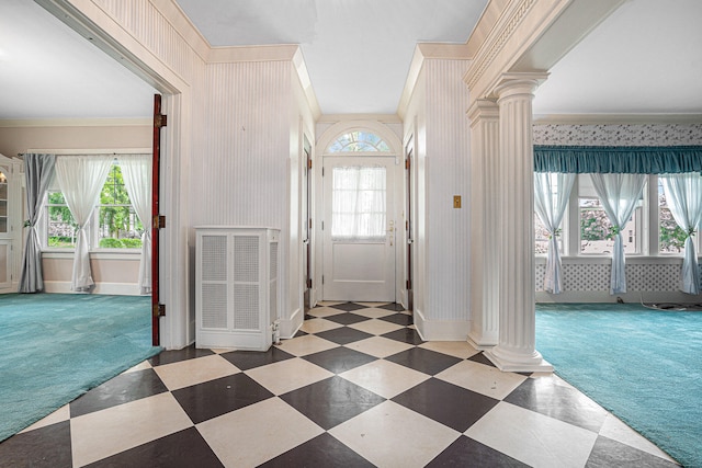 foyer entrance featuring dark carpet, ornate columns, and a healthy amount of sunlight