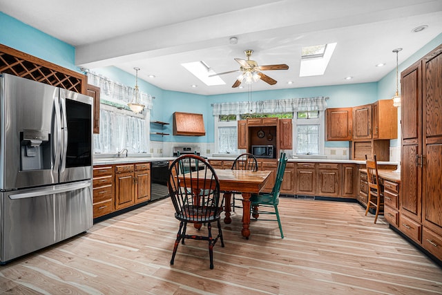 kitchen featuring ceiling fan, decorative light fixtures, a skylight, and appliances with stainless steel finishes