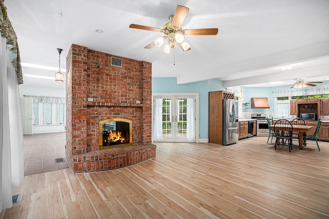 living room with ceiling fan, light wood-type flooring, and a fireplace