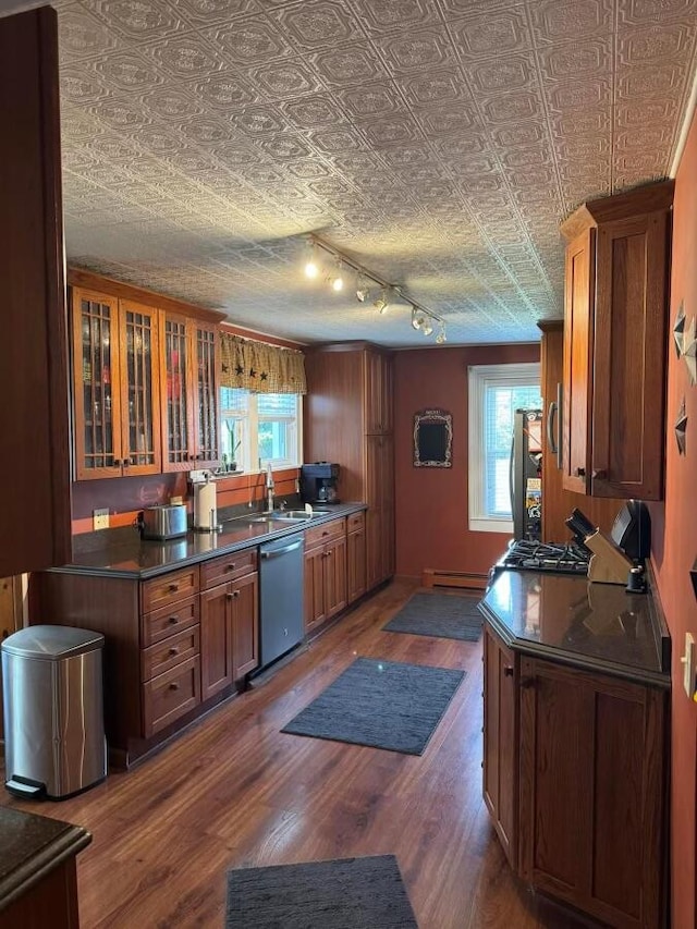 kitchen with a baseboard radiator, appliances with stainless steel finishes, a textured ceiling, dark wood-type flooring, and sink