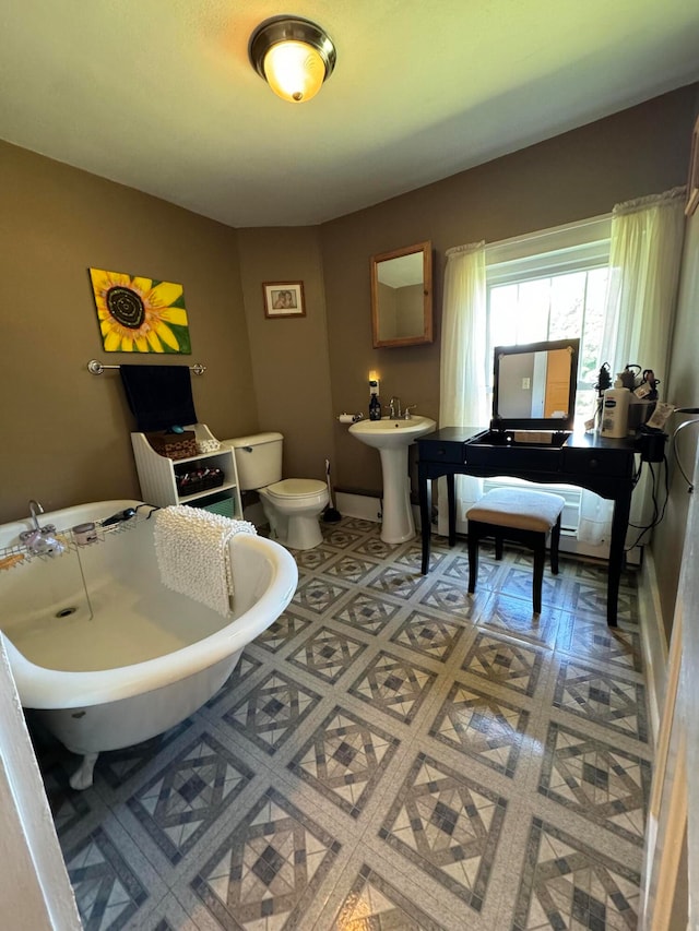 bathroom with a bathing tub, toilet, sink, and tile patterned floors