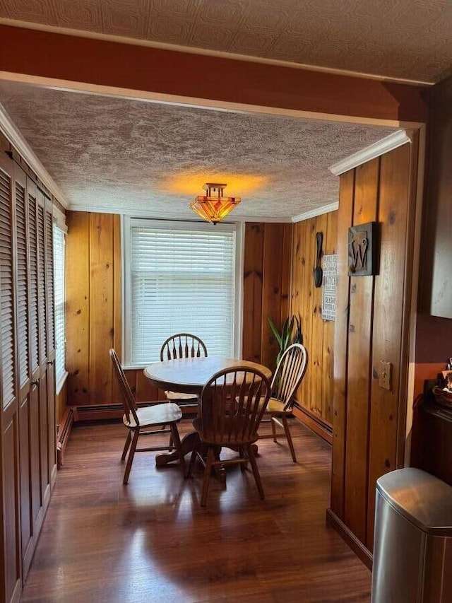 dining room with dark wood-type flooring, a textured ceiling, and wood walls