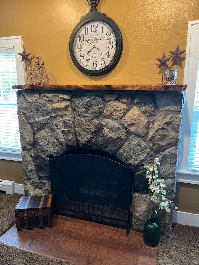 room details with a baseboard heating unit, a fireplace, and wood-type flooring