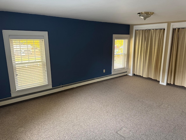 empty room with carpet, a baseboard heating unit, and plenty of natural light