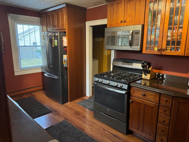 kitchen featuring wood-type flooring, a textured ceiling, appliances with stainless steel finishes, and a baseboard heating unit