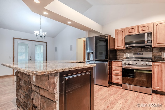 kitchen with decorative backsplash, vaulted ceiling, pendant lighting, stainless steel appliances, and light wood-type flooring