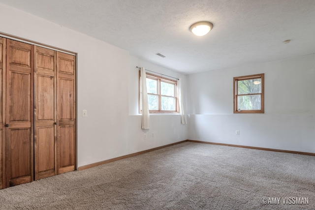 unfurnished bedroom with carpet floors, a textured ceiling, and a closet