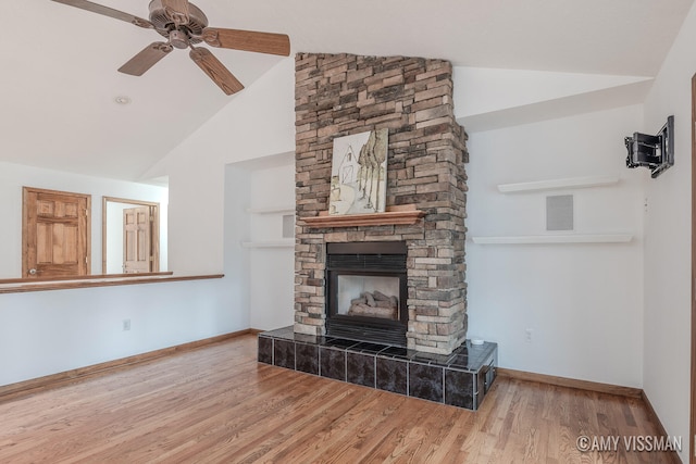 unfurnished living room with wood-type flooring, a stone fireplace, vaulted ceiling, and ceiling fan