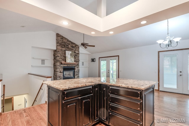 kitchen featuring ceiling fan with notable chandelier, a fireplace, light hardwood / wood-style flooring, and french doors