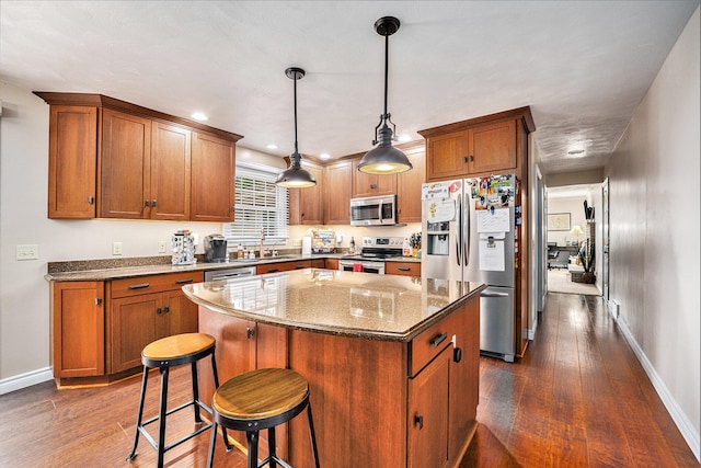 kitchen featuring dark hardwood / wood-style floors, hanging light fixtures, a center island, and stainless steel appliances