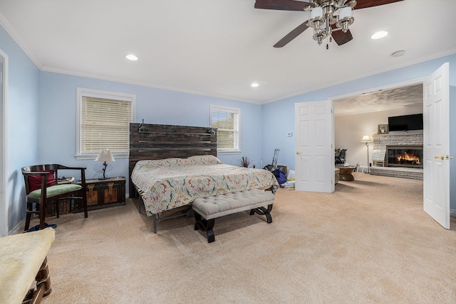 bedroom with light carpet, ceiling fan, crown molding, and a stone fireplace