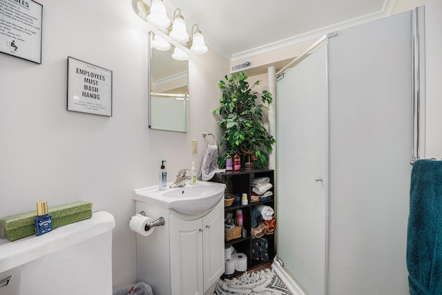 bathroom featuring a shower with shower door, toilet, vanity, and crown molding