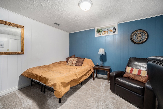 bedroom featuring light carpet, a textured ceiling, and wooden walls