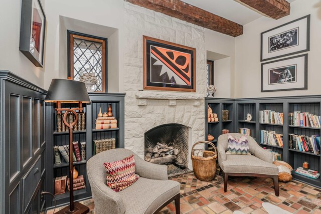 sitting room with a stone fireplace and beamed ceiling