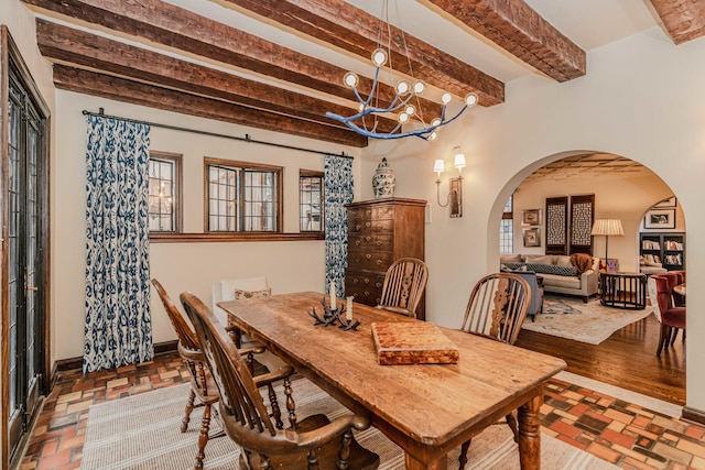 dining area with a chandelier, beamed ceiling, and hardwood / wood-style floors