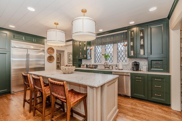 kitchen featuring appliances with stainless steel finishes, light hardwood / wood-style floors, a kitchen island, pendant lighting, and ornamental molding