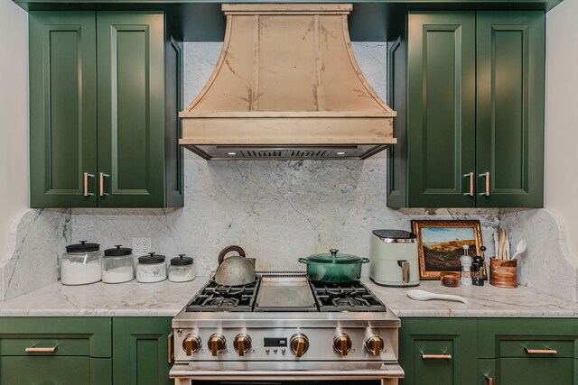 kitchen featuring premium range hood, green cabinetry, tasteful backsplash, and stainless steel range oven