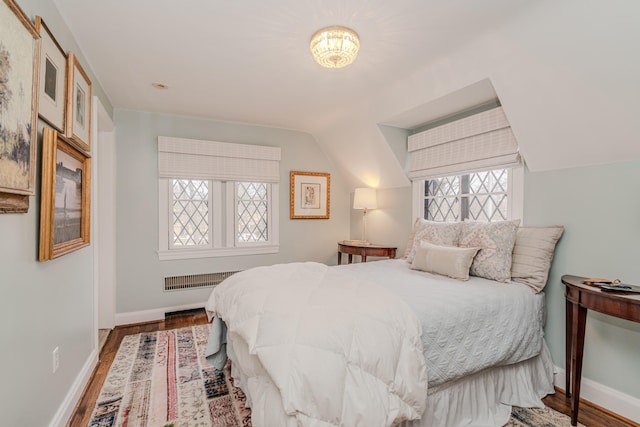 bedroom with wood-type flooring, radiator, vaulted ceiling, and multiple windows