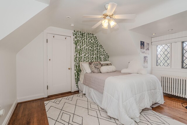 bedroom featuring radiator heating unit, vaulted ceiling, ceiling fan, and light hardwood / wood-style flooring