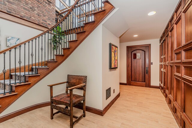 entrance foyer with light wood-type flooring, a high ceiling, and a skylight