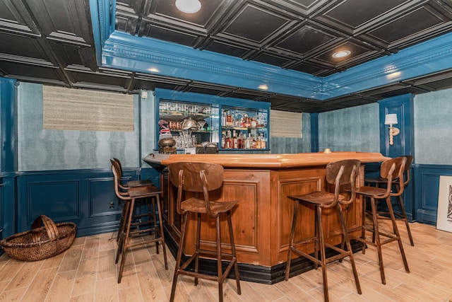 bar featuring blue cabinets, coffered ceiling, and light hardwood / wood-style flooring