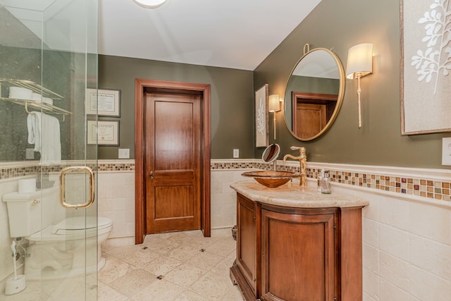 bathroom featuring vanity, tile walls, toilet, and a shower with door