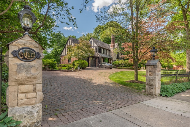 tudor-style house featuring a front yard and a garage