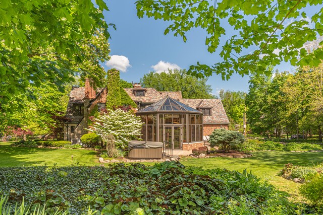 rear view of house with a yard and a hot tub