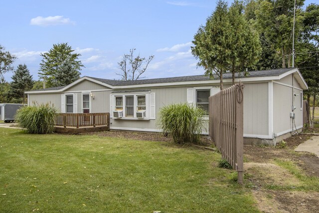 rear view of house featuring a wooden deck and a yard