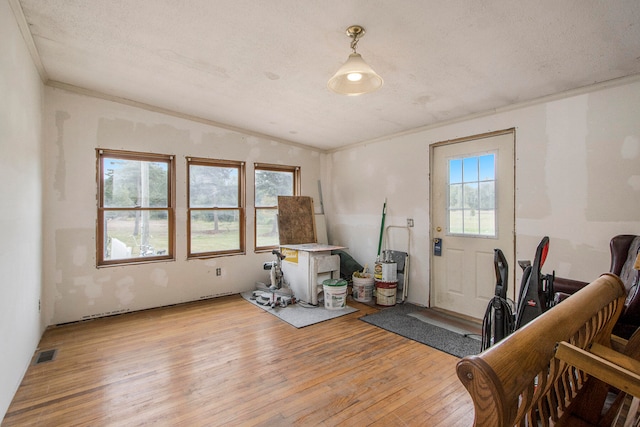 interior space featuring a textured ceiling, crown molding, and light hardwood / wood-style floors