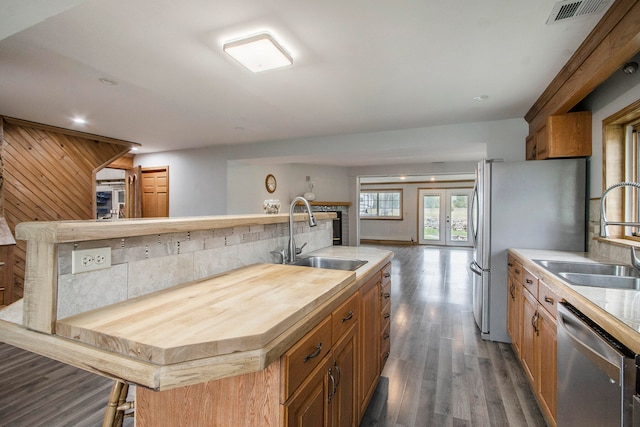 kitchen featuring dark hardwood / wood-style flooring, stainless steel appliances, a kitchen island with sink, and sink