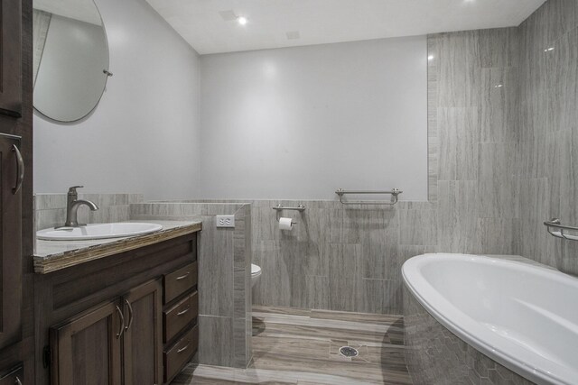 bathroom with tile walls, vanity, and toilet