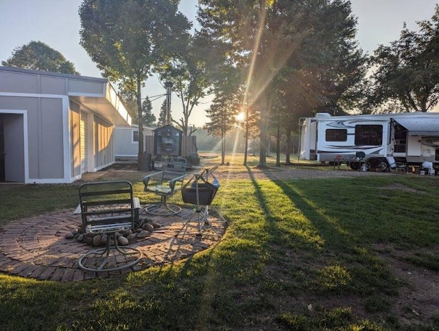 yard at dusk featuring a fire pit, a shed, and a patio area