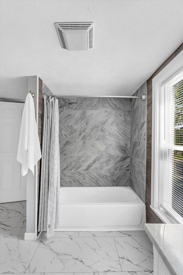 bathroom featuring shower / bathtub combination with curtain and a textured ceiling