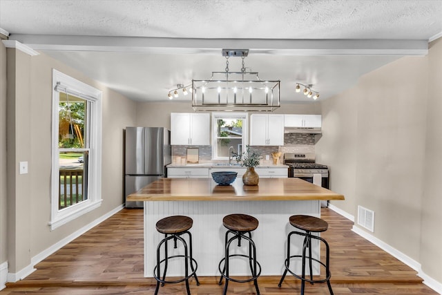 kitchen featuring white cabinets, stainless steel appliances, backsplash, and a kitchen bar