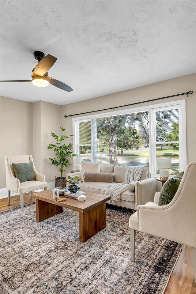 living room with ceiling fan, hardwood / wood-style flooring, a textured ceiling, and a wealth of natural light