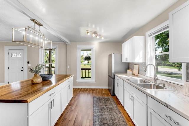 kitchen featuring pendant lighting, white cabinets, sink, dark wood-type flooring, and butcher block counters