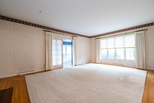 unfurnished room featuring light wood-type flooring, baseboard heating, and plenty of natural light