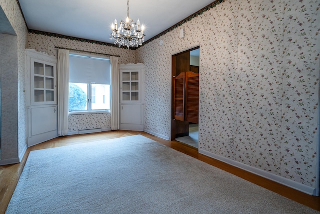 unfurnished room with a notable chandelier, wood-type flooring, and baseboard heating