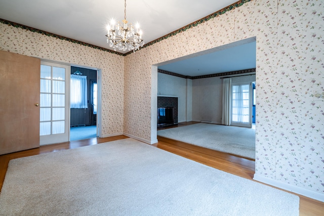 unfurnished living room with hardwood / wood-style floors, a brick fireplace, and plenty of natural light