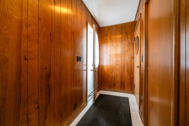 doorway with light tile patterned flooring and wood walls