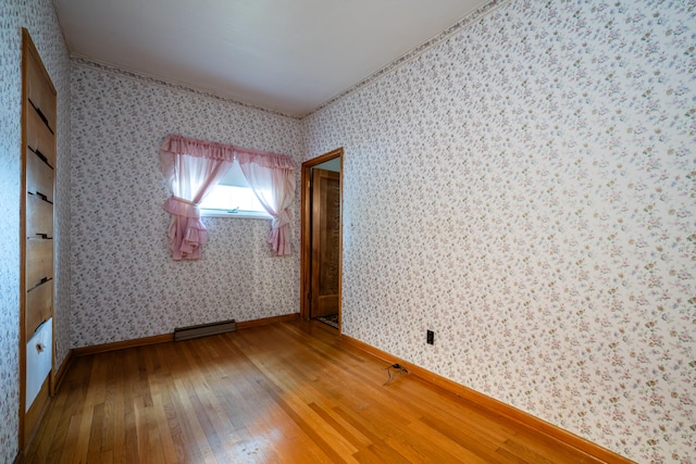 spare room with a baseboard heating unit and wood-type flooring