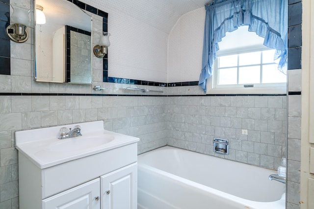 bathroom with tile walls, vanity, and a tub