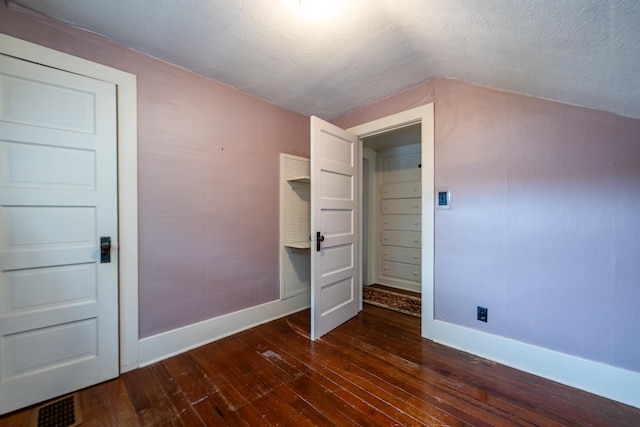 unfurnished bedroom with a textured ceiling and dark wood-type flooring