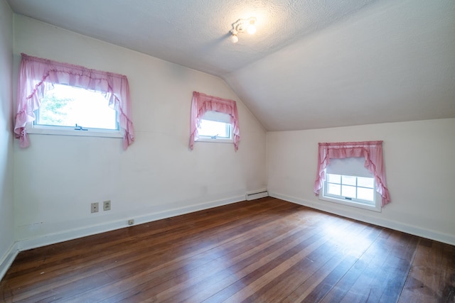 bonus room featuring a baseboard heating unit, a textured ceiling, a healthy amount of sunlight, and dark hardwood / wood-style flooring