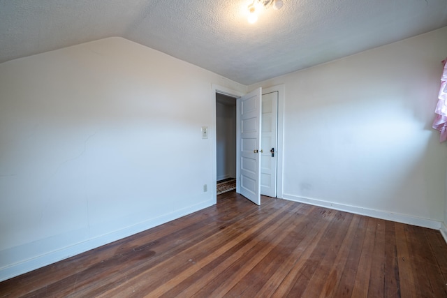 spare room with a textured ceiling, vaulted ceiling, and dark wood-type flooring