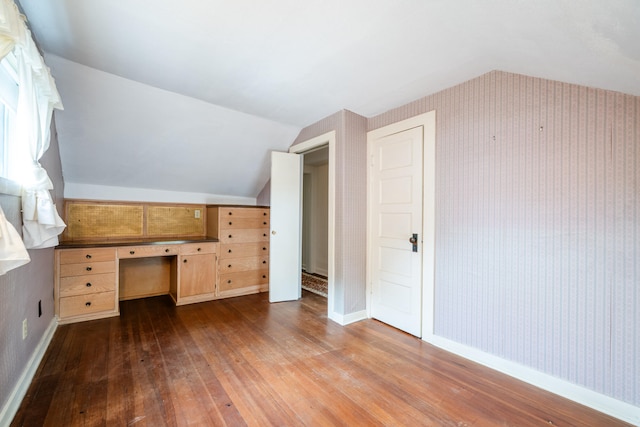 bonus room featuring built in desk, lofted ceiling, and hardwood / wood-style flooring